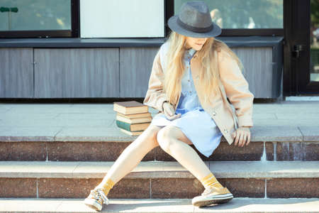 girl with books sitting on the stepsの写真素材