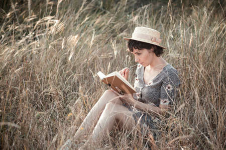 retro style. girl in a hat sits and reads a bookの写真素材