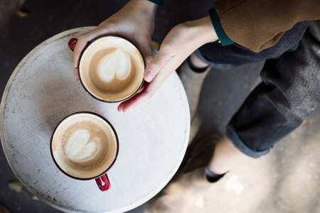 two red cups of coffee on the table and the legs of the girlの写真素材