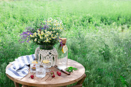 breakfast in the garden. on the table is a vase of flowers and glasses of lemonadeの写真素材