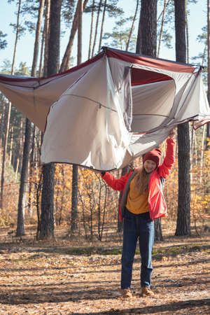 happy girl tourist holding a tent in the forestの写真素材