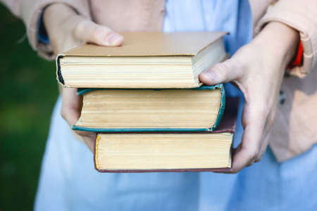 girl holding a stack of books and coffee in her handsの写真素材