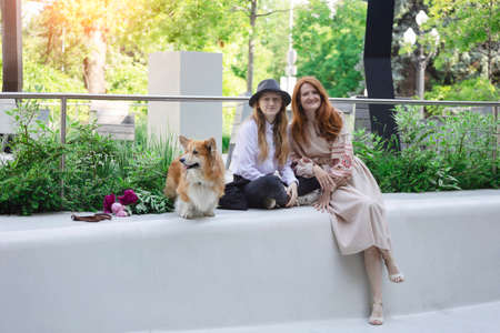 happy family outdoors. Mother, daughter and beautiful corgi dog look at the cameraの写真素材