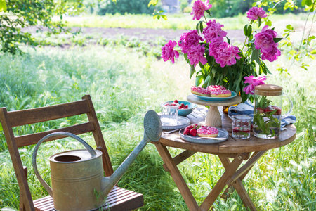 garden and tea party at the country style. still life - donuts, dishes and a vase with pink peonies
