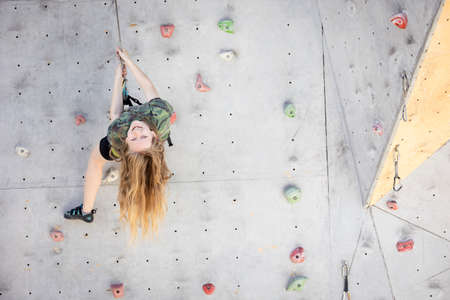 sport. bouldering, teen girl climbing up the wallの写真素材