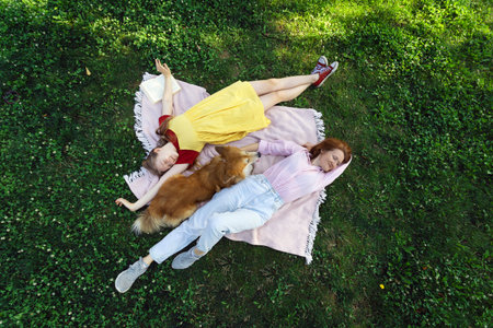girls and corgi dog lie on the lawn