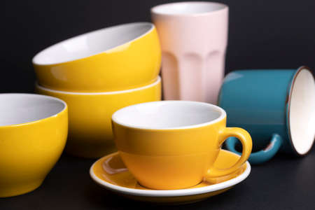 bright ceramics - bowl and cups in yellow, blue, and pink colors on a black backgroundの写真素材