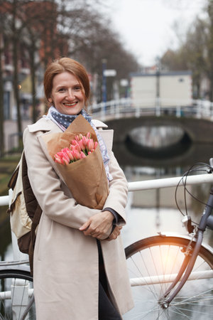 happy smiling girl holding a bouquet of tulips standing on a street of Amsterdam. The Netherlandsの写真素材