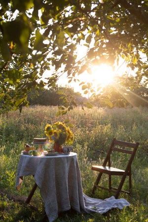 garden and still life. tea party in the garden - pie, vase with sunflowers and apples on a table