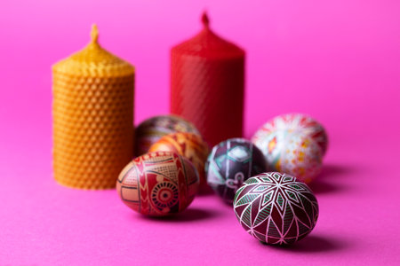 happy easter card. beautiful Easter egg Pysanka handmade and candles on a pink backgroundの写真素材