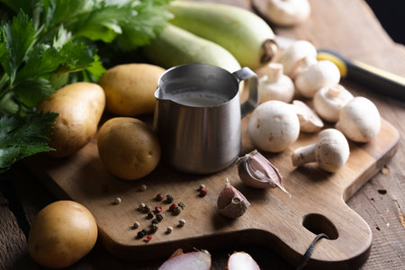 ingredients for soup on a wooden table - potatoes, cream, zucchini, onion, celeryの写真素材