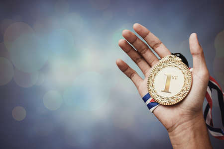 hand holding up a gold medal as a winner in a competitionの写真素材