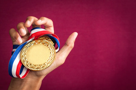 hand holding up a gold medal as a winner in a competitionの写真素材