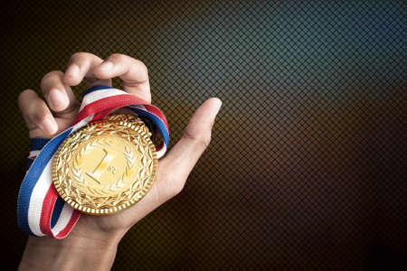 hand holding up a gold medal as a winner in a competitionの写真素材
