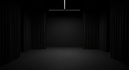 The image depicts a dimly lit corridor with tall, black walls. The floor is also dark, and there is a single, narrow light at the end of the corridor, casting a faint glow. The atmosphere is mysterious and somewhat eerie.の素材