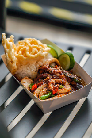 The appearance of fried squid chili sauce with rice, crackers and cucumber is very deliciousの写真素材