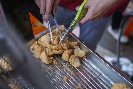 Fried meatballs are being cut into pieces using scissorsの写真素材
