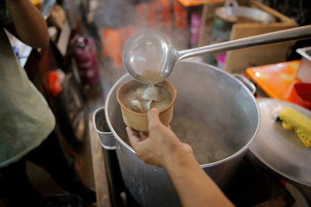 A trader is serving meatballs into bowls for his customerの写真素材