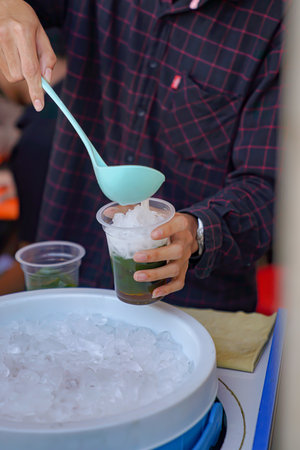 A green grass jelly seller is serving green grass jelly to buyersの写真素材