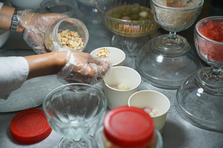 A trader is pouring peanuts into a white styrofoam bowl for wedang rondeの写真素材