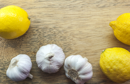 Three Lemons and white garlics on woodの写真素材