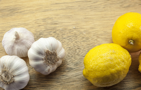 Three Lemons and white garlics on woodの写真素材