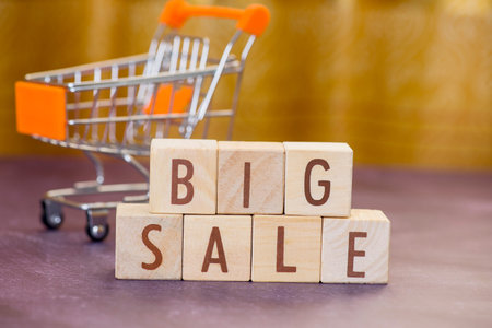 Wooden cube block big sale word with mini shopping cart blurred background