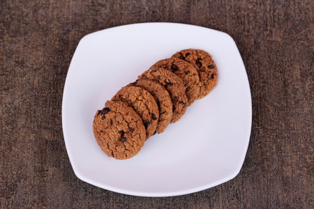 Close up of chocolate chip biscuits served in a plate and isolated on a dark background.の写真素材