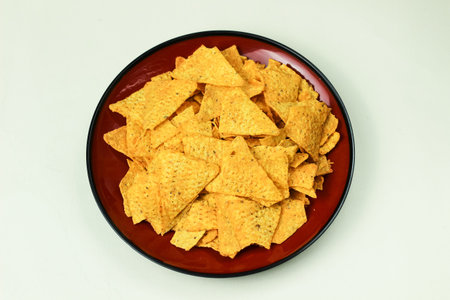 Close up of chips served on a plate and isolated on a white background with a top angle shot.