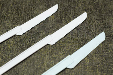 Serrated cake knife. Serrated cake knife made of plastic on a dark, textured background. Close up.の写真素材