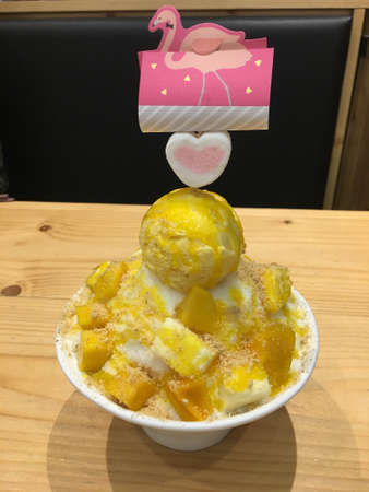 Soft ice with sliced of sweet mango with crushed nuts for dessert. Not forgetting a scoop of mango flavored ice creamの写真素材