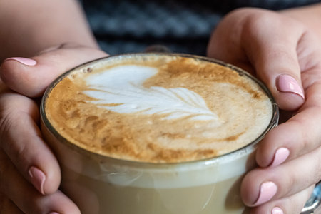 Big cappucino cup with coffee art on a foam with woman hands