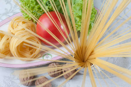 still life with fettuccine, spaghetti, nuts, tomato leaves and lettuce leavesの写真素材