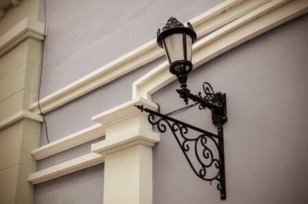 Street lamp mounted on the walls of the building in vintage toneの写真素材