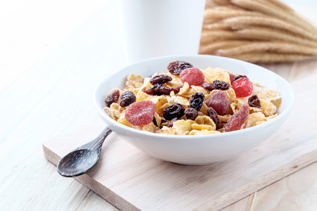 cornflakes and dry berry fruits in a white bowl on a wooden background.の写真素材