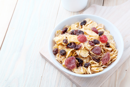 cornflakes and dry berry fruits in a white bowl on a wooden background.の写真素材
