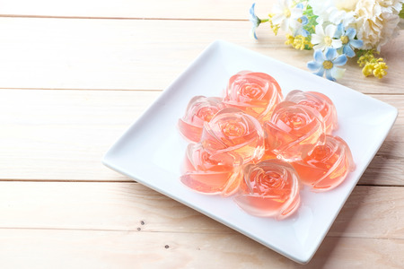 Jelly in rose shape in plate on wooden backgroundの写真素材