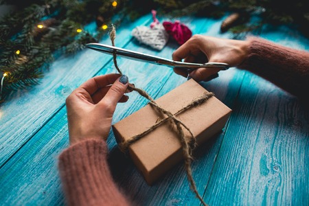 Concept of Christmas items on a blue wooden table. Woman's hands wrapping Christmas gift.の写真素材