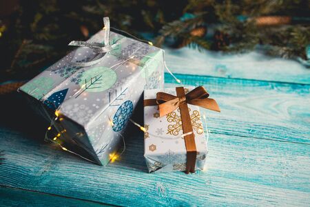 Christmas presents on blue wooden table with fir sprigs and Christmas lights. の写真素材