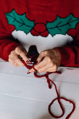 Woman in red Christmas sweater knits in cold winter dayの写真素材