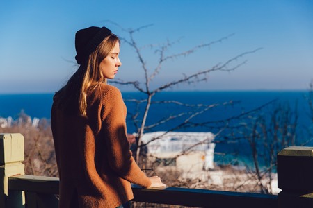 Fashionable dressed young woman dreaming about something by the sea. Outdoors.の写真素材