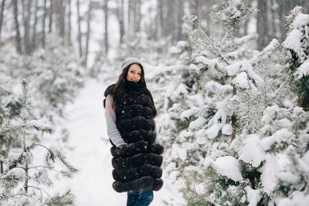 Woman in winter fur vest walking in winter forest in snowy cold weatherの写真素材