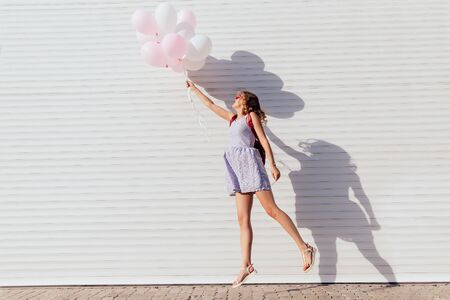 Funny woman jumping with air balloons, having fun outdoors, wearing summer dress. Profile.の写真素材