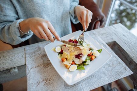Woman eats a delicious Caesar salad in a restaurant. Closeupの写真素材