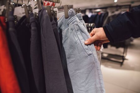 Shopping in men's clothing store. Man chooses clothes in clothing store. Shopping conceptの写真素材