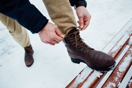 Shoelaces of boots. Man tying shoelaces on winter boots in winter dayの写真素材