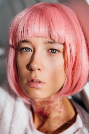 Close-up portrait of attractive young model, looking pensively at camera, with pink short haircut.の写真素材