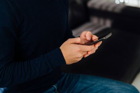 Young man holds a mobile phone, close-up.の写真素材