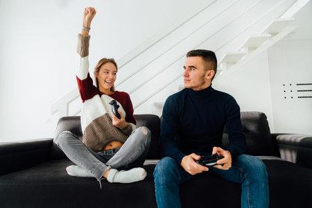 Cheerful beautiful girl celebrate winning and raised his fist up after playing computer games with...