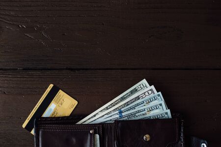 Dollars cash. Open male wallet with dollars cash and credit card on brown wooden table with copy space for your designの写真素材